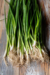 A bunch of spring green onion on wooden table, top view close up