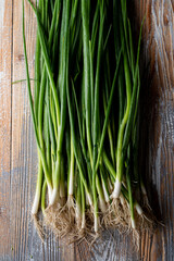 A bunch of spring green onion on wooden table, top view close up