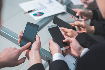 close up . employees with smartphones analyzing financial data.