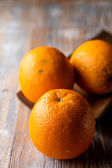 Three whole oranges on a wooden table, close up, grocery store photo catalogue