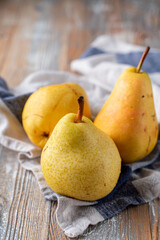 Three big yellow pears on rustic kitchen table, close up, bright atmospheric photo