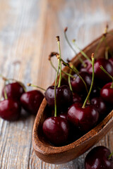 A whole wooden bowl of ripe seasonal black cherries, close up, side view, advertisement appetizing photo