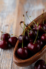A whole wooden bowl of ripe seasonal black cherries, close up, side view, advertisement appetizing photo