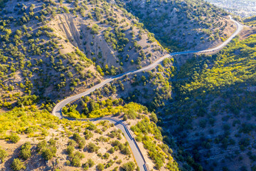 Mountainous area. The winding road runs along a steep slope. Shooting from the air.