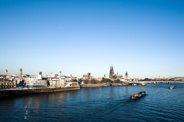 Naklejka premium The river Rhine with the cathedral of Cologne in Germany in winter with snow on a sunny day.