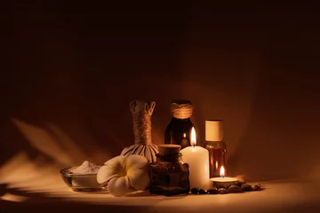 Fotobehang Beautiful spa composition with candles, frangipani flower, oil flasks, bowl with salt and herbal ball. © gudenkoa