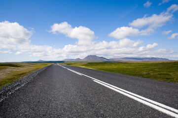 Clean asphalt road in island towards horizon with blue sky