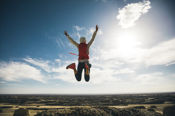 Successful woman trail runner jumping on on sand desert dunes