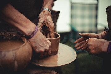 close up of hands of a potter and his student learning pottery