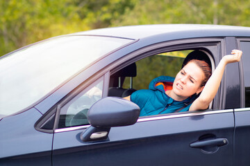 Angry aggressive woman, female emotional annoyed driver shouts, while driving a car, waving her hand from the car window. Driving anger, negative emotions, aggression, traffic jam