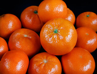 A bunch of fresh tangerines on a black background.