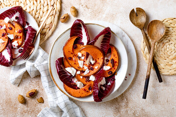 Roasted pumpkin salad with radicchio leaves, feta cheese, nuts and cranberries. Thanksgiving side dish dinner recipe. Healthy seasonal fall or autumn food