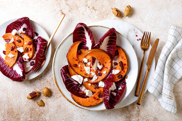 Roasted pumpkin salad with radicchio leaves, feta cheese, nuts and cranberries. Thanksgiving side dish dinner recipe. Healthy seasonal fall or autumn food