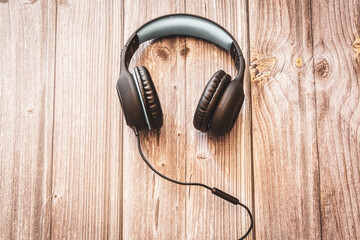 A pair of headphones resting on a rustic wooden background with copy space