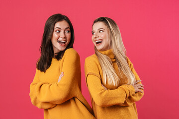 Image of excited beautiful women smiling while standing back to back