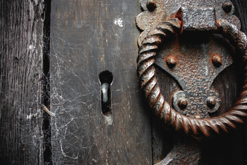 Old rusty handle and keyhole on an old church door with spider webs.