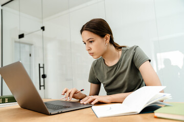 Obraz na płótnie Canvas Image of thinking student girl doing homework with laptop