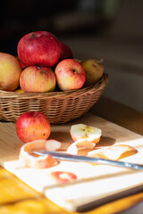 fall apple composition, wicker basket filled with red and yellow apples, peeled apple it front