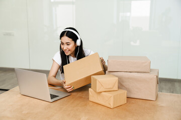 Photo of asian delivery assistance working with packages and laptop