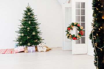Fototapeta na wymiar Stylish Christmas scandinavian minimalistic interior Christmas tree with light and bauble in sunny living room