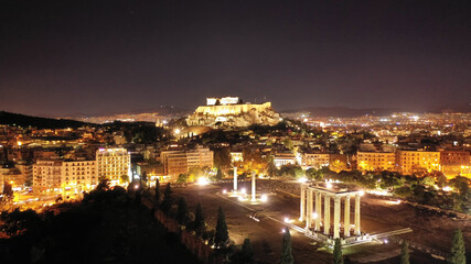 Fototapeta premium Aerial drone night shot of illuminated iconic Temple of Olympian Zeus and Acropolis hill and the Parthenon at the background, Athens, Attica, Greece