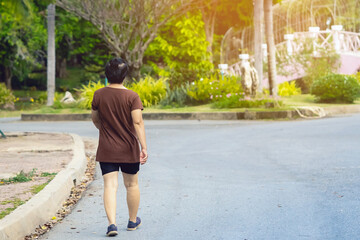 Fototapeta premium Back view portrait of a Asian elderly woman walking and jogging for good health in public park. Senior jogger in nature. Older female enjoying Peaceful nature. Healthcare concept