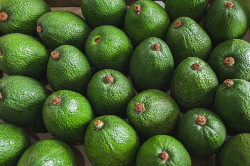 Fresh avocados on the vegetable market top view. Healthy food concept.