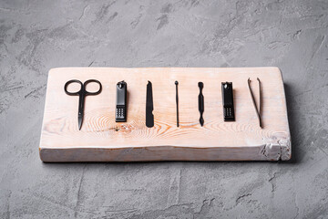 Set of manicure, pedicure tools and accessories on wooden board, stone concrete background, angle view