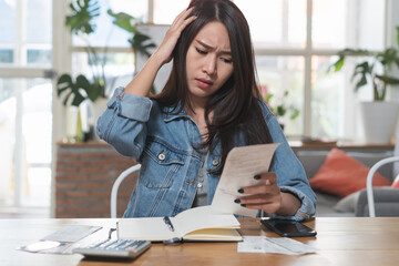 Woman looking at receipt in her hands and worry about finance.
