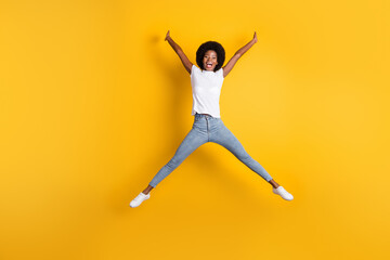 Full length body size photo of amazed surprised girl with black skin jumping high pretending star laughing isolated on bright yellow color background