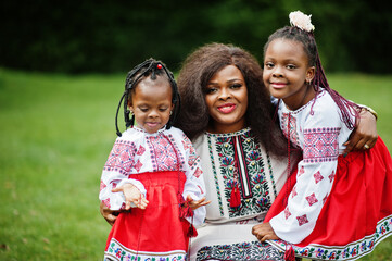 African mother with daugters in traditional clothes at park.