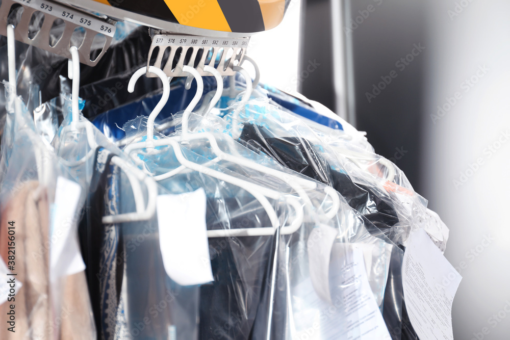 Wall mural Hangers with clothes on garment conveyor at dry-cleaner's, closeup