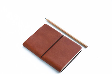 Selective focus of brown leather cover notebook and sharp pencil on isolated background