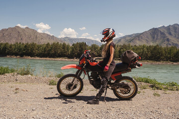 Woman traveling by enduro motorcycle in mountains road