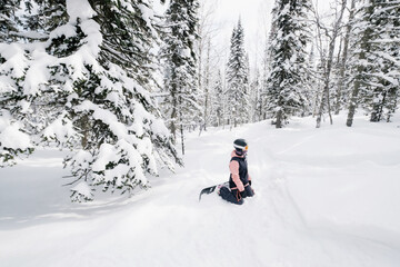 Fototapeta na wymiar snowboarder woman rest during snowboarding in winter snow-covered fur forest, fresh snow powder, freestyle freeride on sunny winter day
