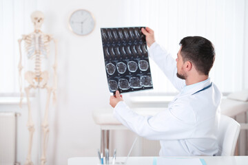 Orthopedist examining X-ray picture at desk in clinic