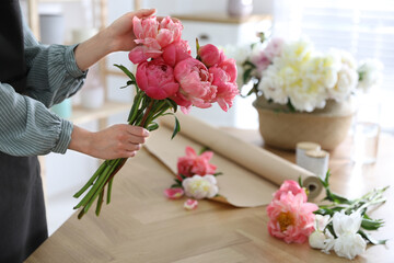 Florist making beautiful peony bouquet at table, closeup
