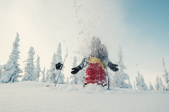 snowboarder female in snow-cowered trees  winter forest have fun and tossing snow