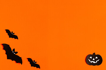 Fototapeta na wymiar silhouettes of bats and pumpkins made of black paper on an orange background, Halloween concept, ready-made layout with space for text, copy space. Flat lay for your design