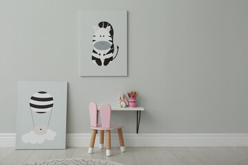 Stylish child's room interior with adorable paintings, small table and chair. Space for text