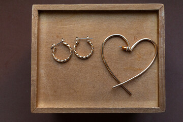 heart shaped golden earring and golden small earrings on wooden box