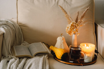 Still life details in home interior of living room. Pumpkin and cup of tea with candles on a serving tray. Rest and Reading
