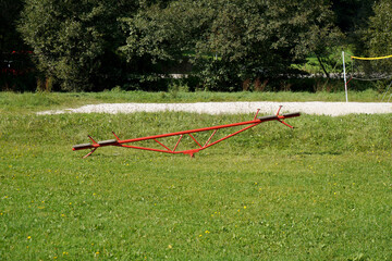 View of a red seesaw on a green field