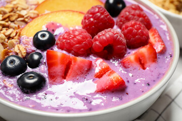 Delicious acai smoothie with fruits and oatmeal in bowl, closeup