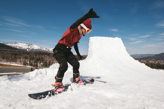 Snowboarder female jumping on quarter pipe snowboard in winter sunny day. Freestyle snowboard training
