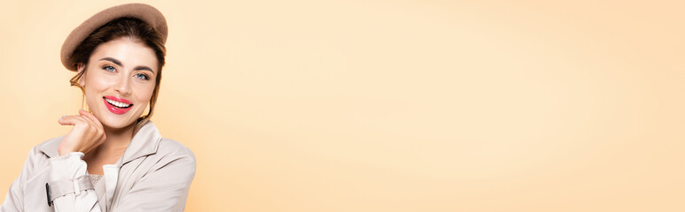 panoramic shot of joyful, trendy woman in autumn outfit looking at camera isolated on peach