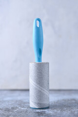 White lint roller for cleaning clothes on a grey background. Reusable adhesive tape for removing wool, hair and dirt from sweaters, dresses. Wardrobe preparation neat person.