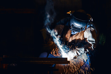 Industrial welder welding fabricated construction in factory, Welding process by Shielded Metal Arc Welding (SMAW) or Stick Welding.