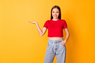 Photo of attractive lady hold open palm presenting novelty wear casual red top jeans isolated over yellow color background