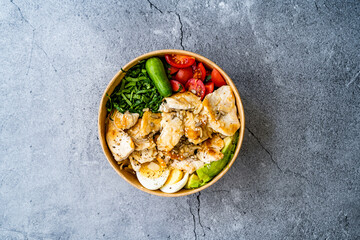 Healthy Protein Fitness Food Chicken, Egg, Spinach, Avocado and Cucumber with Fitness Equipment Dumbbells for Athlete in Plastic Bowl.